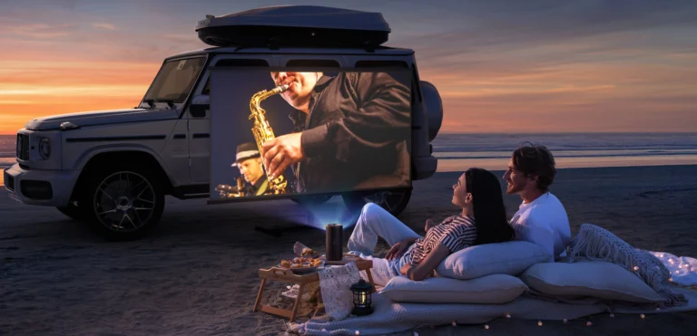 A couple watching a movie on a beach using an Anker Nebula portable projector