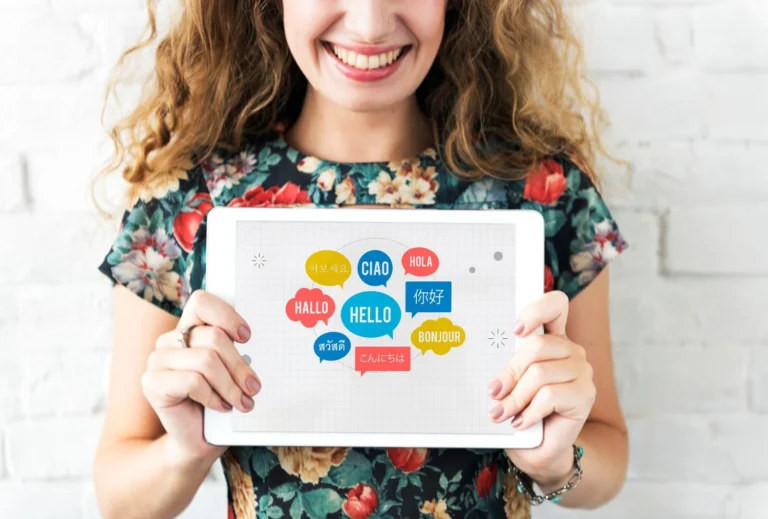 woman holding a tablet displaying speech bubbles in different languages - the best language learning apps